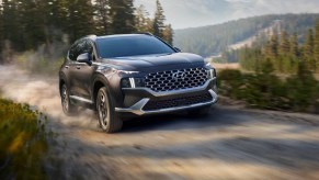 A gray 2023 Hyundai Santa Fe Hybrid midsize hybrid SUV is driving off-road.