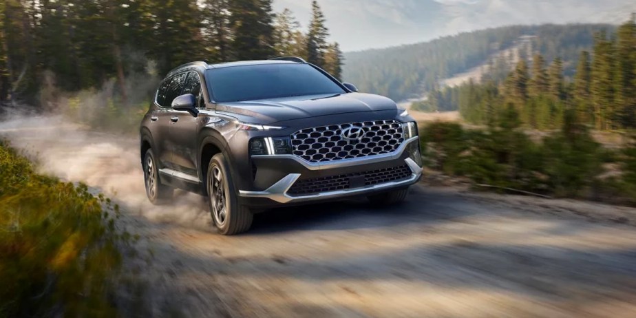 A gray 2023 Hyundai Santa Fe Hybrid midsize hybrid SUV is driving off-road.