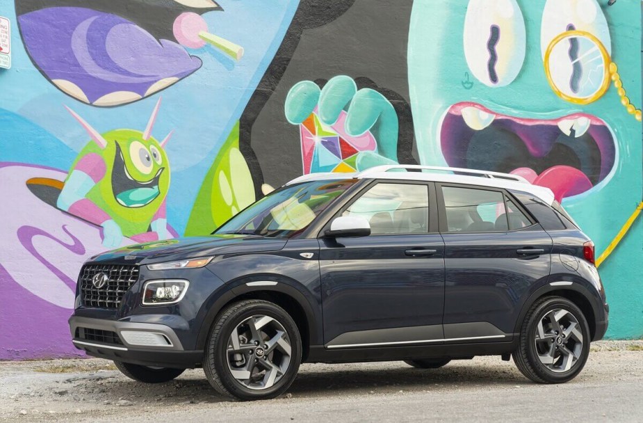 A gray 2023 Hyundai Venue shows off its side profile against a painted wall. 