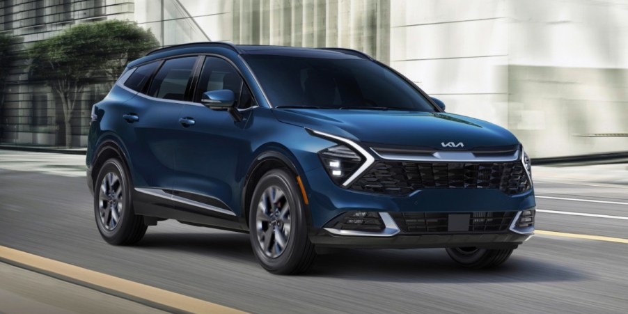 A blue 2023 Kia Sportage Hybrid small hybrid SUV is driving on the road.