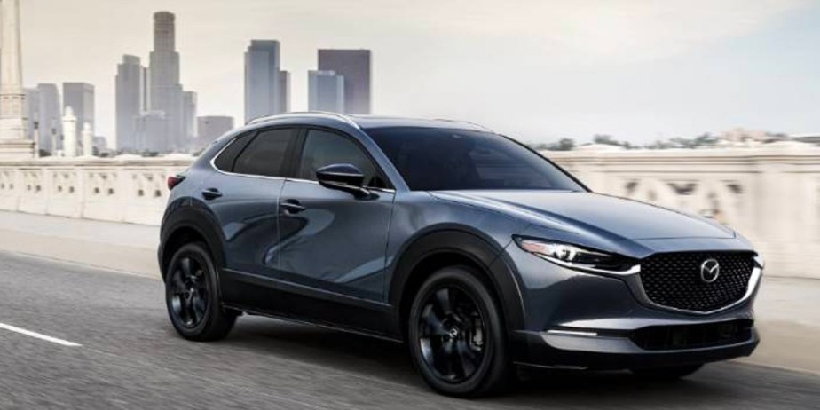 A blue 2023 Mazda CX-30 subcompact SUV is driving on the road. 