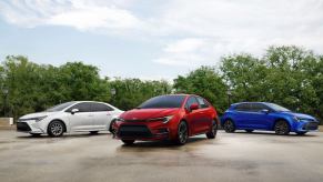 A white 2023 Toyota Corolla sedan, red 2023 Toyota Corolla Hybrid, and blue 2023 Toyota Corolla Hatchback