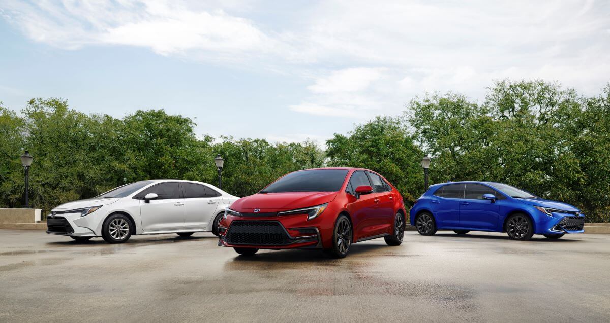 A white 2023 Toyota Corolla sedan, red 2023 Toyota Corolla Hybrid, and blue 2023 Toyota Corolla Hatchback