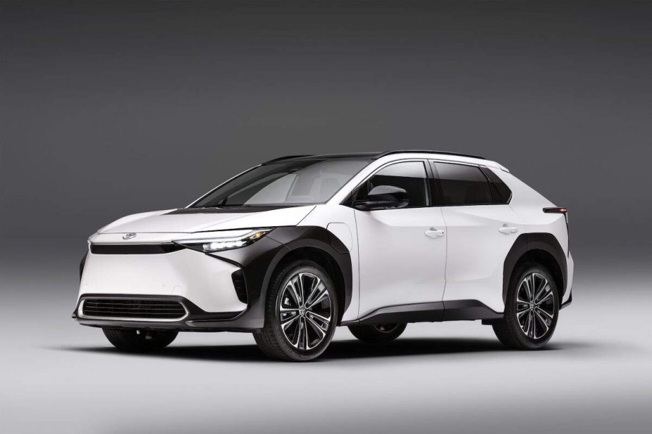 A white Toyota bZ4X parked indoors in front of a black and white background. 