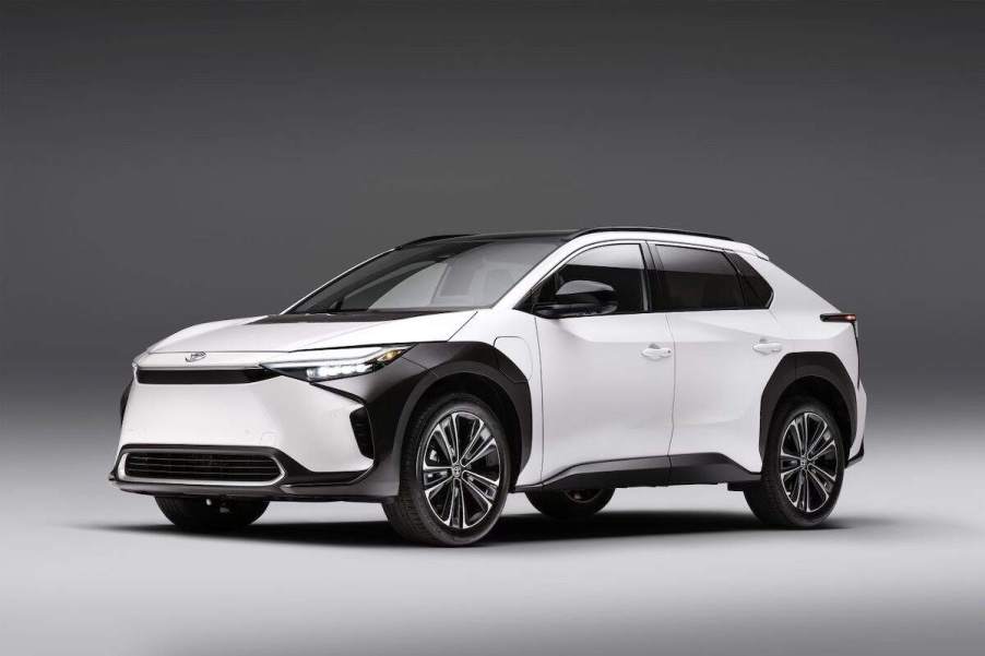 A white Toyota bZ4X parked indoors in front of a black and white background.