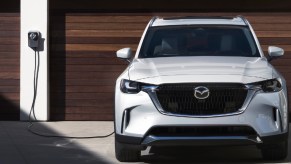 A white 2024 Mazda CX-90 PHEV midsize plug-in hybrid SUV is charging.