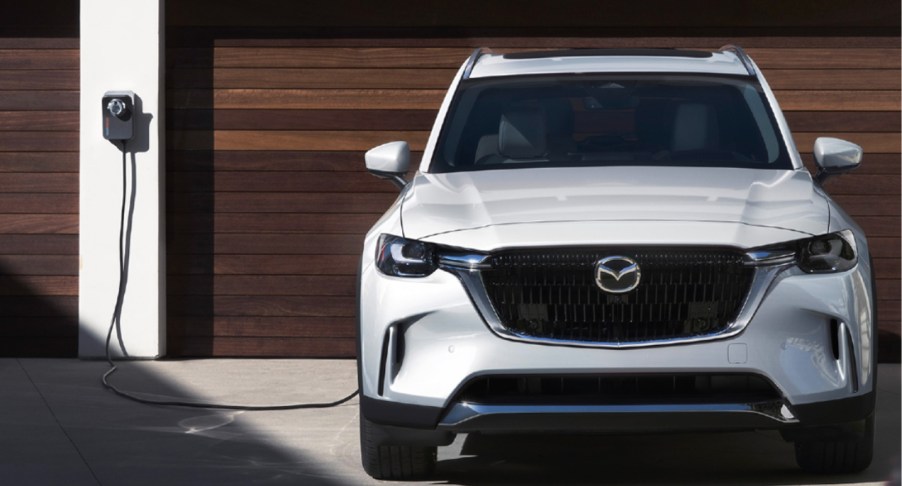 A white 2024 Mazda CX-90 PHEV midsize plug-in hybrid SUV is charging.