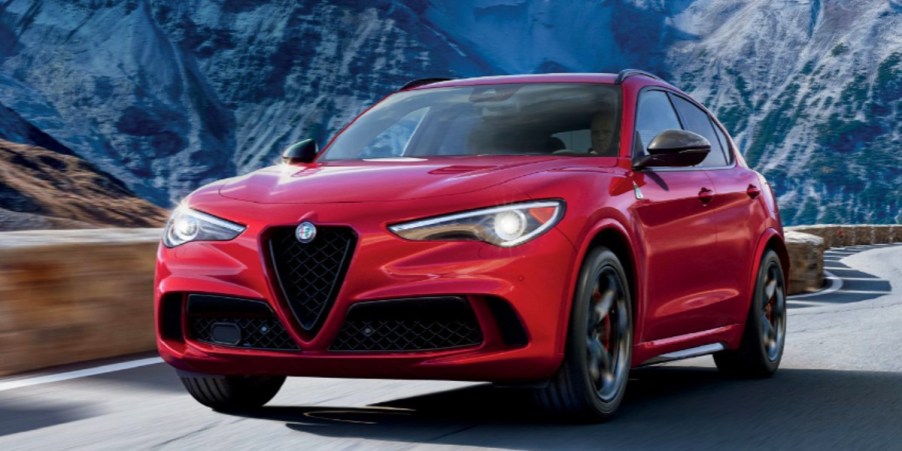 A red Alfa Romeo Stelvio Quadrifoglio compact luxury SUV is driving on the road.