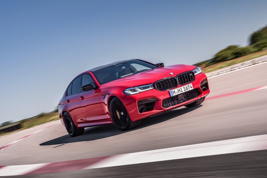 A red BMW M5 sedan is fast around a test track. 