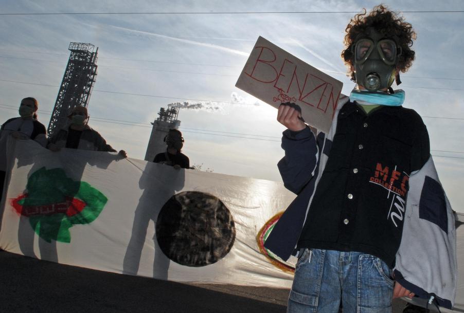 A Serbian boy holds a cardboard with the word "Benzene' written on it. This is one of the chemicals that makes gasoline smell good to us.