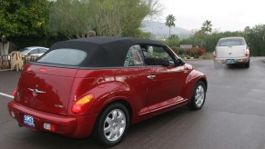 Two early convertible PT Cruisers driving away from the camera for a press event.