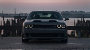 A dark gray Dodge Challenger SRT Hellcat shows off its dual-snorkel hood at sunset.