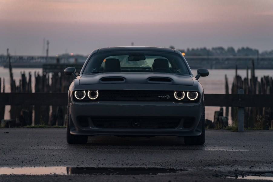 A dark gray Dodge Challenger SRT Hellcat shows off its dual-snorkel hood at sunset.