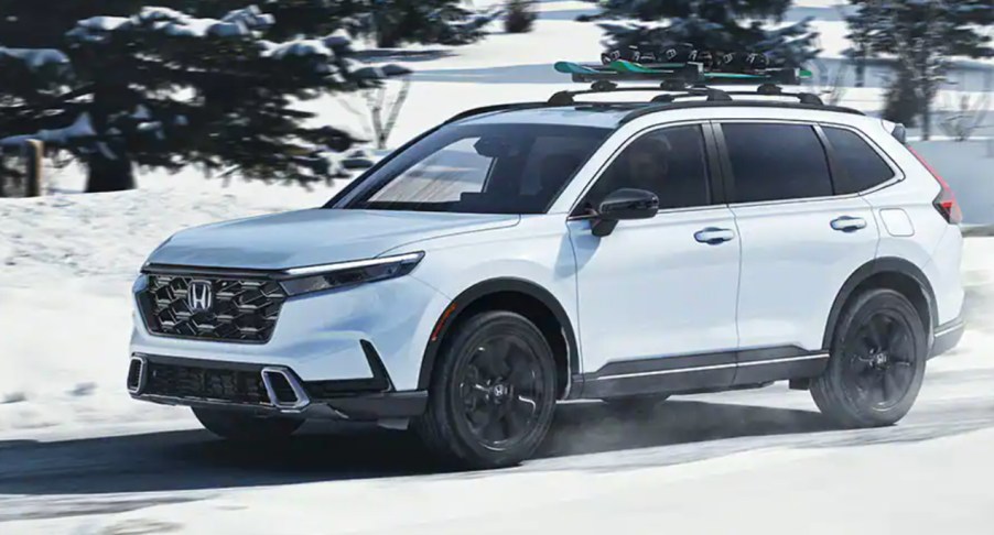 A white 2023 Honda CR-V is driving in the snow.