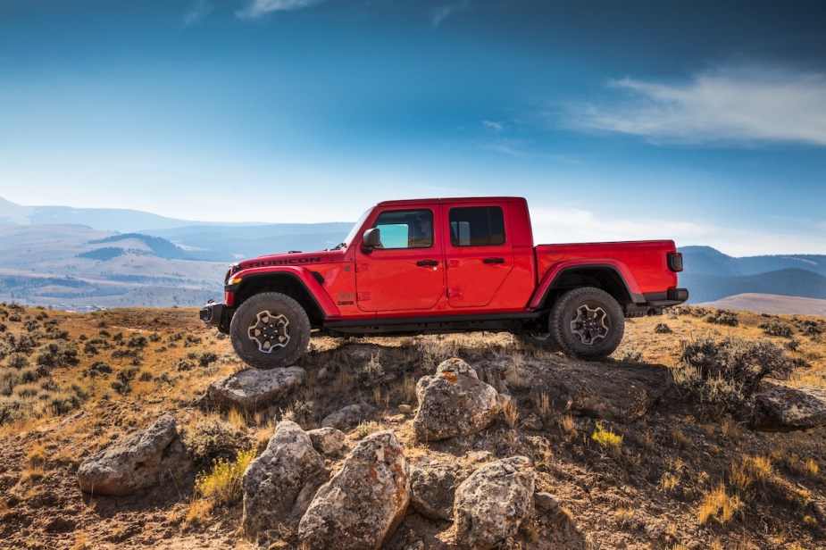 A red 2023 Jeep Gladiator parked outdoors, it is a midsize  truck with a standard V6 engine.