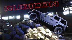 A Jeep Rubicon climbing on a constructed rock in front of a Rubicon sign.