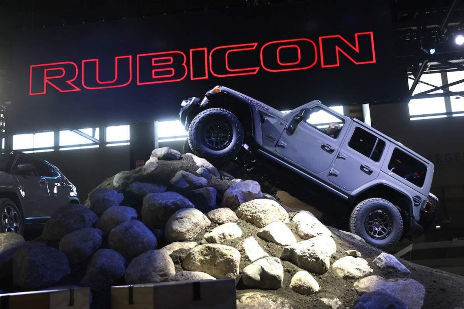 A Jeep Rubicon climbing on a constructed rock in front of a Rubicon sign. 