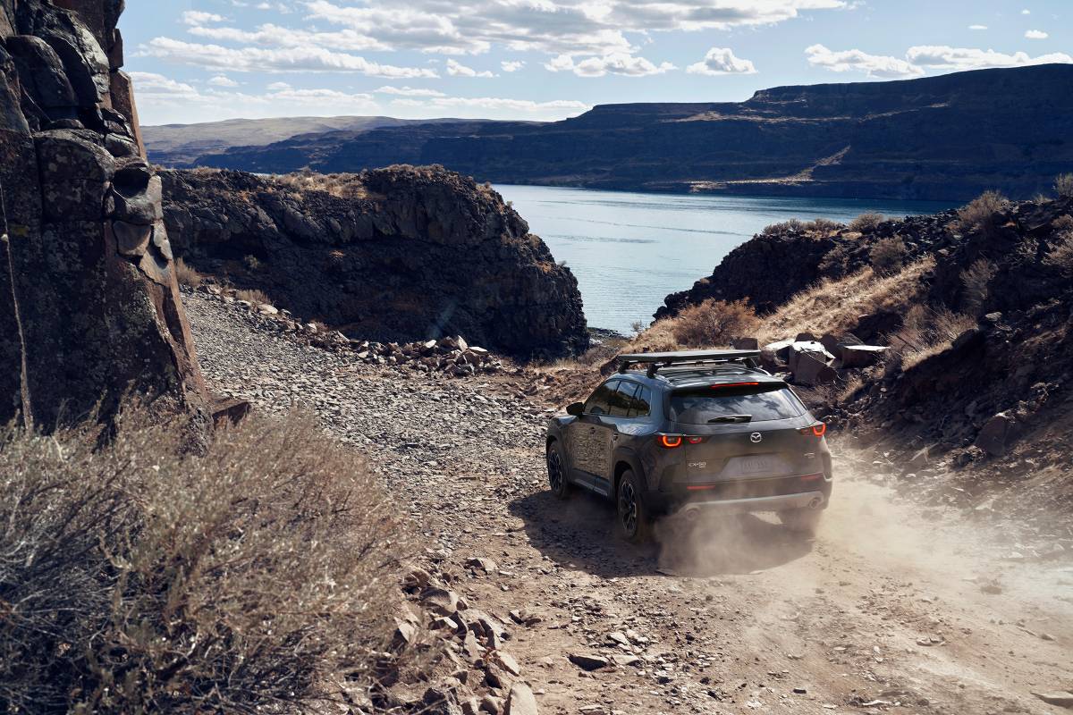 A 2023 Mazda CX-50 driving down a gravel road.