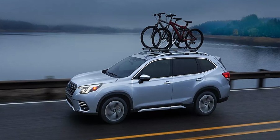 A blue Subaru Forester small SUV is driving on the road.