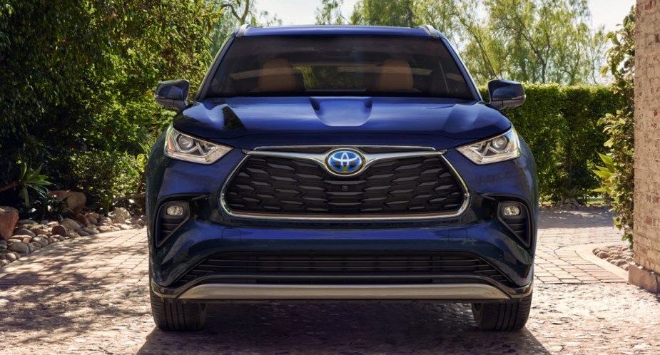 A blue 2023 Toyota Highlander Hybrid midsize hybrid SUV is parked outside. 