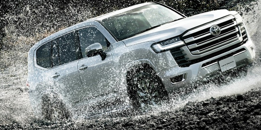 A gray Toyota Land Cruiser full-size SUV is driving through the water.