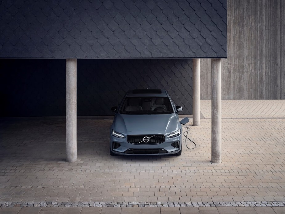 A gray Volvo S60 Recharge hybrid car charges under an awning.