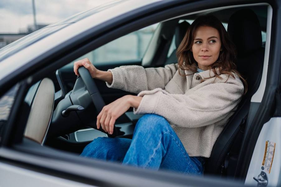 A woman driver sitting in the front seat of her Tesla car.