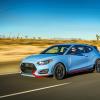 A light blue with red trimming 2022 Hyundai Veloster N performance hatchback model driving down a desert highway