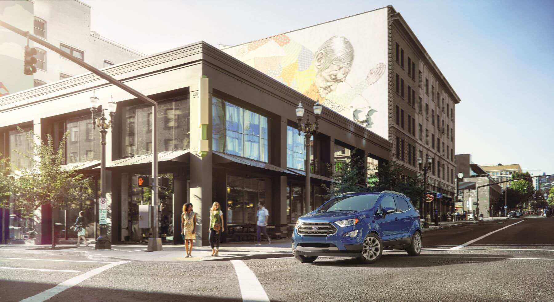 A blue 2022 Ford EcoSport subcompact crossover SUV model stopped at a crosswalk