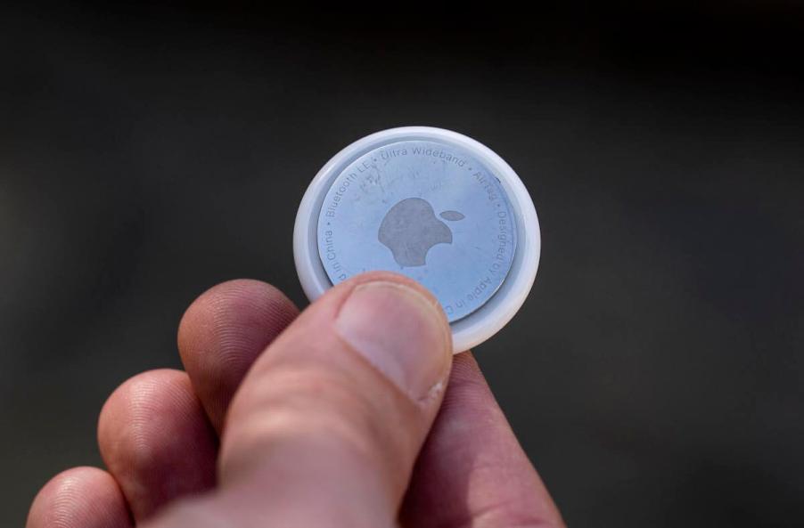 A man holds an Apple Airtag.