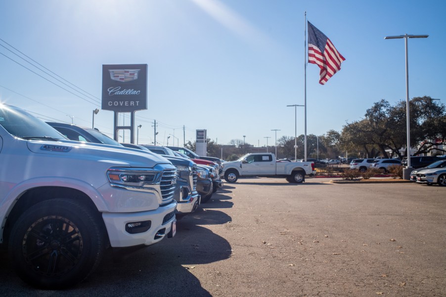 A row of various pickup trucks parked at a dealership, an American flag visible in the background.