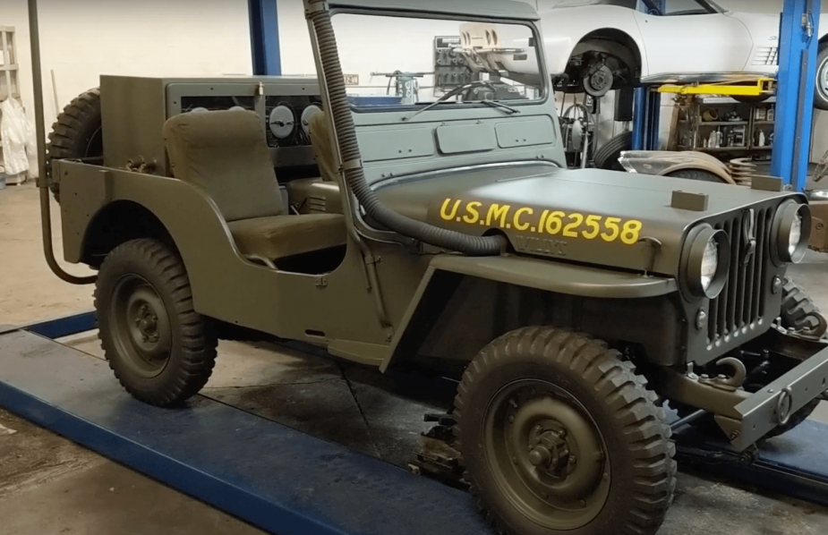 A military green 1950 Jeep CJ35/U underwater 4x4 SUV parked in a restoration shop