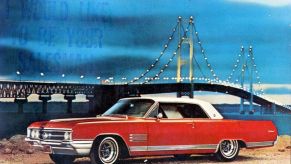 A red 1964 Buick Wildcat on a General Motors (GM) postcard with the Golden Gate Bridge