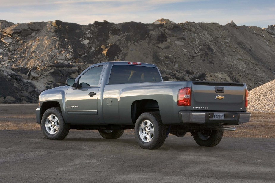 The back of a gray Chevrolet Silverado parked in a sandpit site.