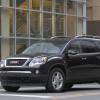 A black 2010 GMC Acadia midsize SUV model stopped at a light or stop sign