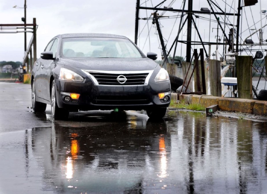 A black 2013 Nissan Altima cruises wet streets with questionable reliability.