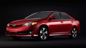 A red 2014 Toyota Camry poses against a dark backdrop.