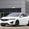 A white 2021 Acura ILX parked in front of a gray building.