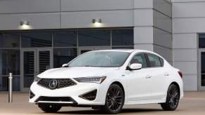 A white 2021 Acura ILX parked in front of a gray building.