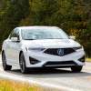 A white 2021 Acura ILX driving down a wooded country road.