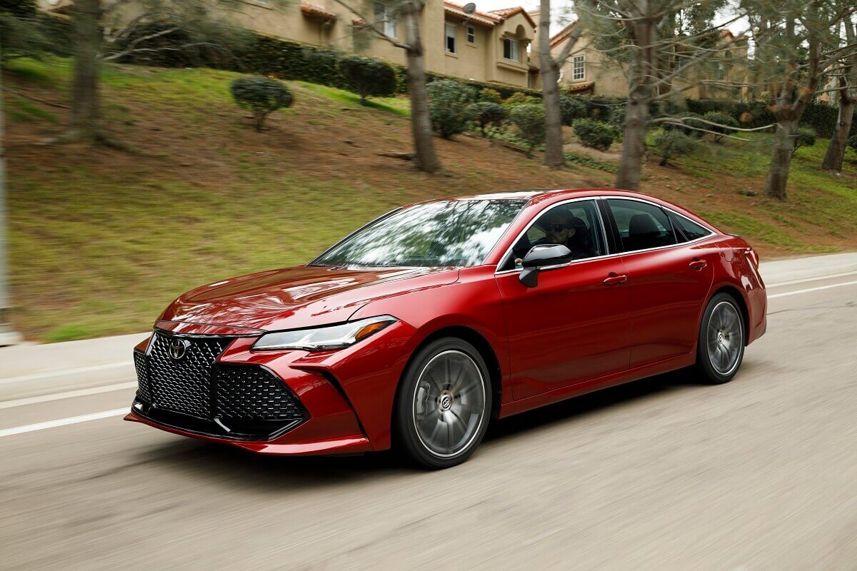 A red 2022 Toyota Avalon full-size car cruises down a country road.