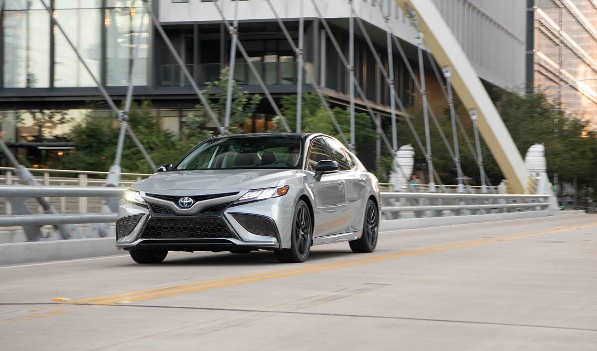 A silver Toyota Camry drives down a city street.