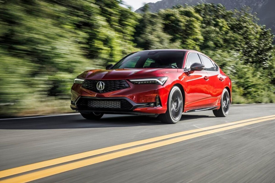 A red 2023 Acura Integra sports car shows off its liftback while it cruises down a safe back road. 