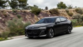 A black 2023 BMW 760i drives down a road