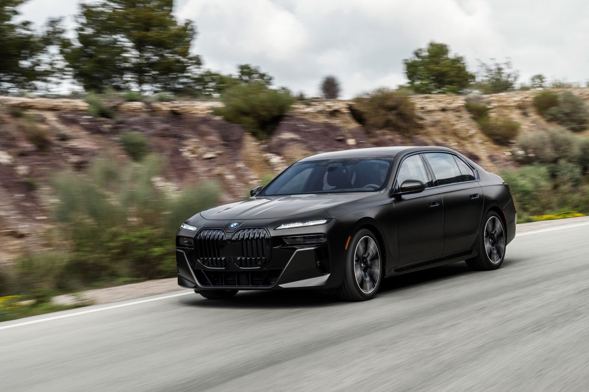 A black 2023 BMW 760i drives down a road 