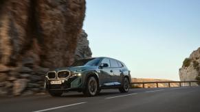 A new 2023 BMW XM drives along a desert mountain road.