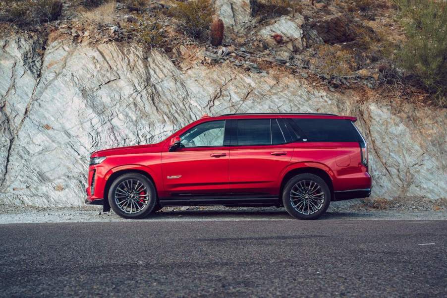 A red 2023 Cadillac Escalade, a full-size third-row luxury SUV that could be best for you, parked out doors in a rocky mountainous area.