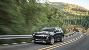 A black 2023 Chevrolet Blazer drives down a country road