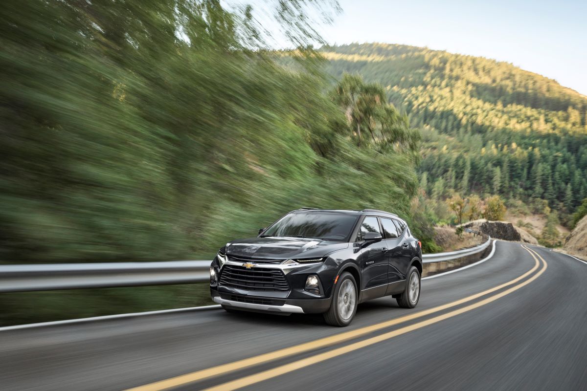 A black 2023 Chevrolet Blazer drives down a country road