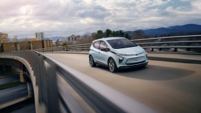 A light blue Chevy Bolt drivers on a highway toward the camera.